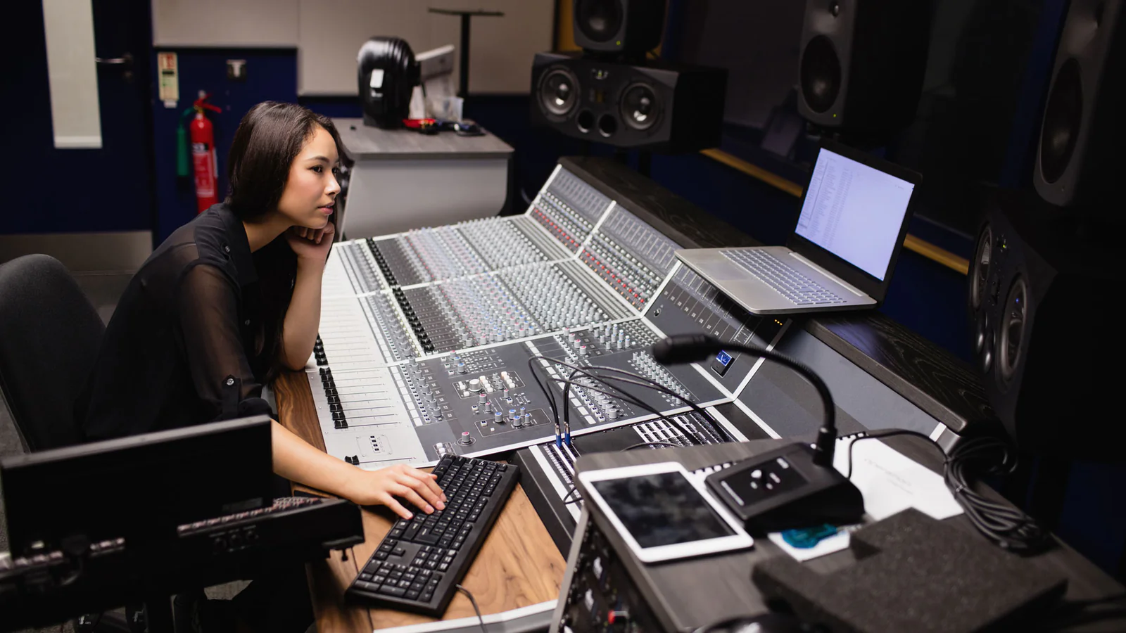 Mujer trabajando en una consola de mezcla profesional en un estudio de grabación.